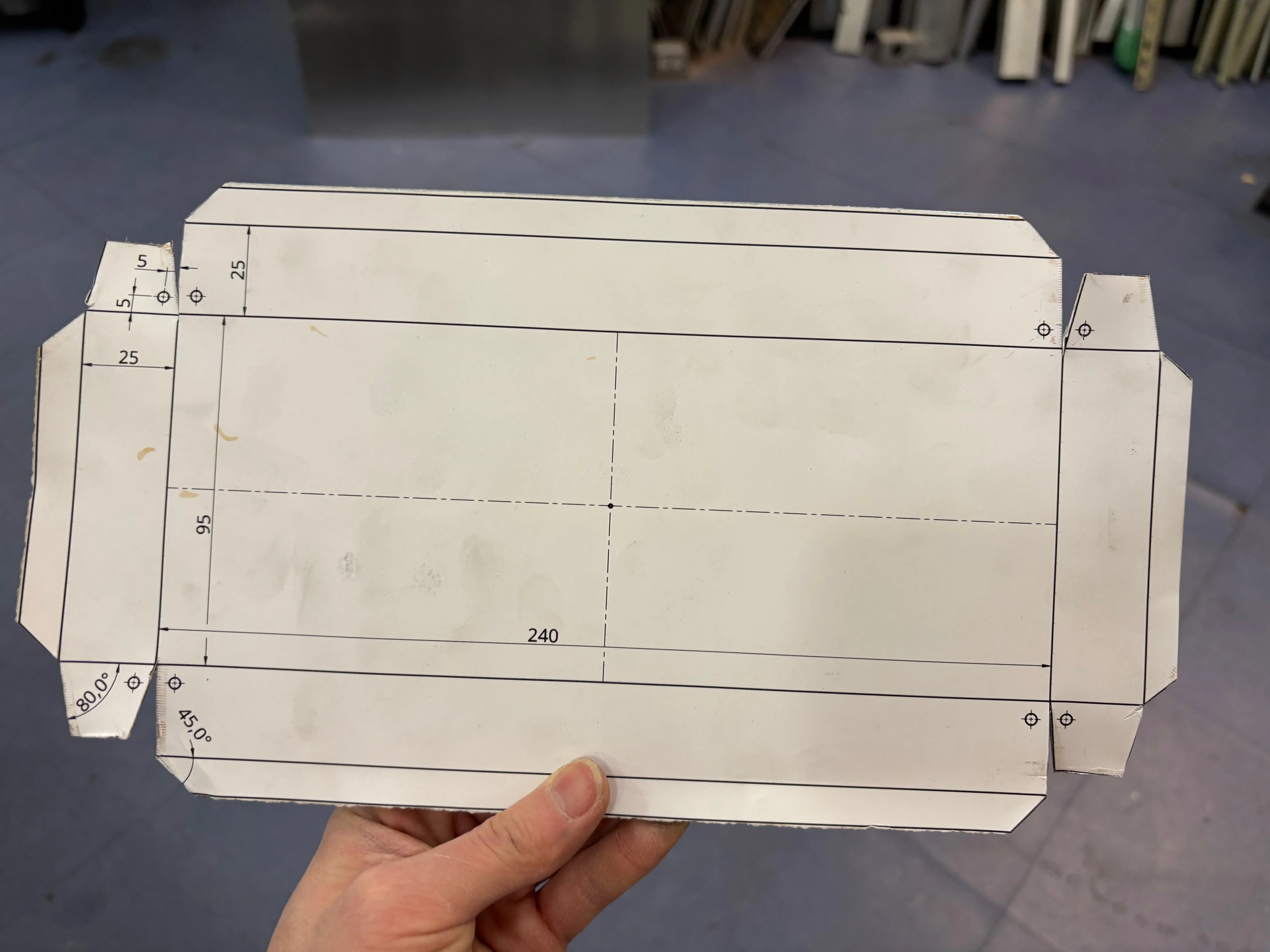 Piece of cut sheet metal with paper template stuck on the front